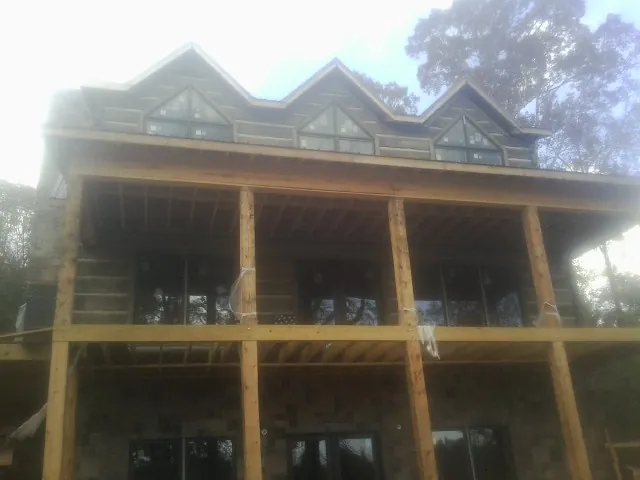 Dormers and porch framing on a large log home under construction — Roof Coating work by our crew in Scribner