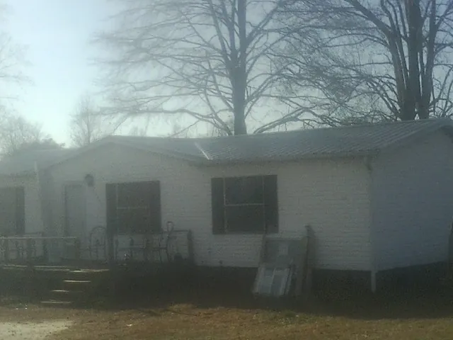 New metal roof on a white painted brick home on a foggy morning in Scribner