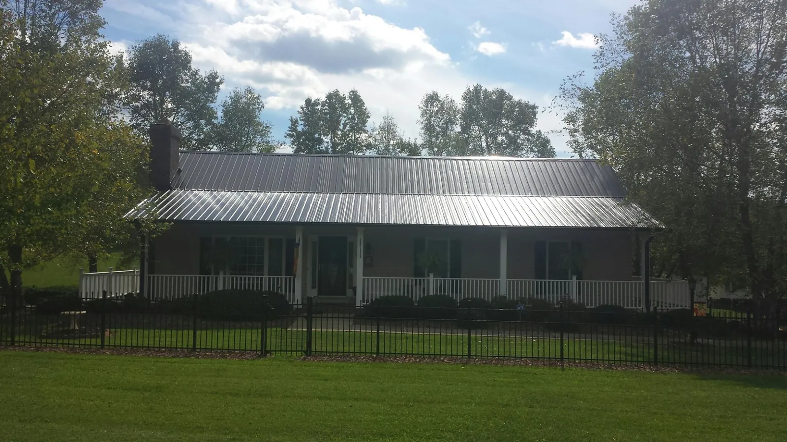 Gray metal roof on a brick ranch with a full width front porch — Gutter Guard Installation work by our crew in Scribner